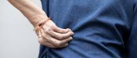 person touching their lower back